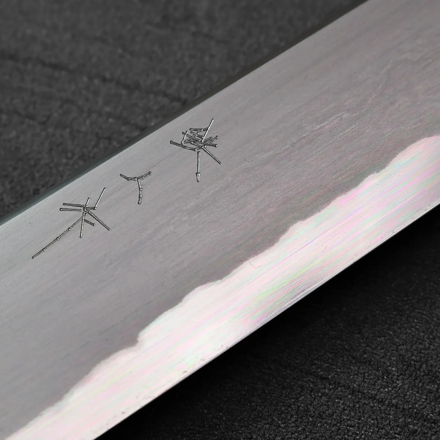 Close-up of sujihiki blade, 240mm, with engraved characters in focus.