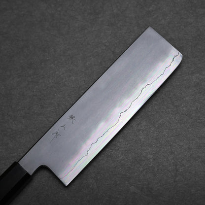 A Japanese vegetable knife, or nakiri knife, with a rectangular blade featuring a wavy pattern and engraved Japanese characters, lies on a dark textured surface.