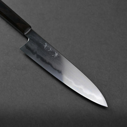 A Japanese-style kitchen knife with a polished blade featuring a wavy pattern and engraved characters, displayed on a dark gray background for an elegant presentation.