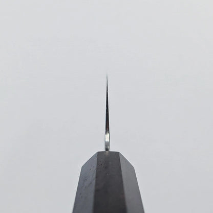Choil shot of a knife blade photographed from above, with the edge aligned vertically against a plain white background for a striking minimalist composition.
