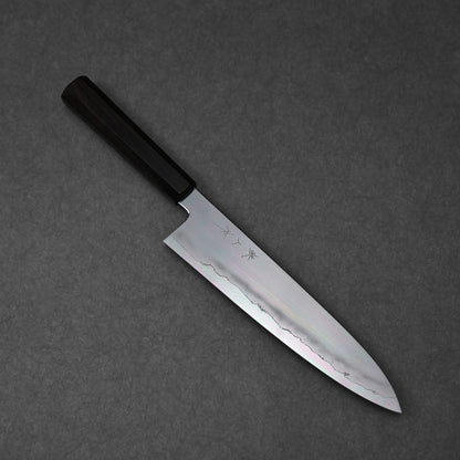 Gyuto knife made with ginsan steel; shown in diagonal orientation to highlight the full blade profile and handle and engraved kanji characters near the handle.