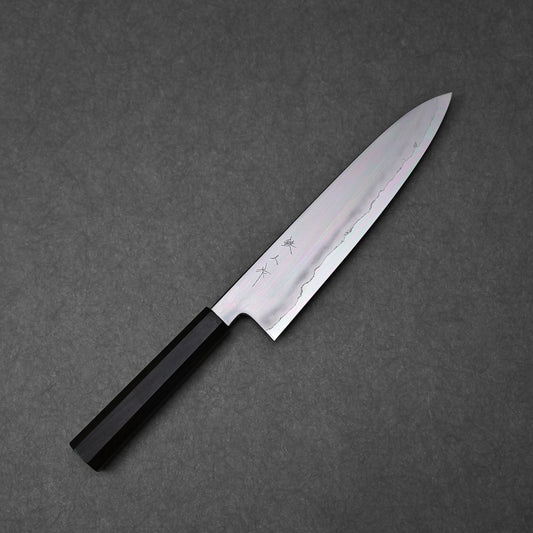 Gyuto knife made with ginsan steel; photographed to show the full blade profile and handle, emphasizing the refined steel finish, engraved kanji near the handle, and balanced design.