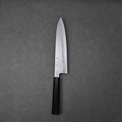Gyuto knife made with ginsan steel; photographed in vertical orientation to show the full blade profile and handle, with visible hamon pattern and engraved kanji characters near the handle.
