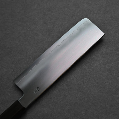 Nakiri knife photographed from the reverse side, showing a smooth steel surface with three vertically engraved kanji characters near the spine; close-up angle emphasizes finish clarity and traditional craftsmanship.