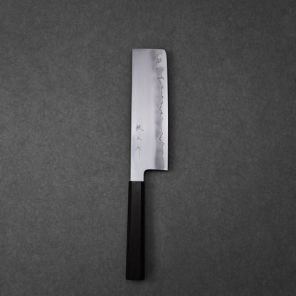 Nakiri knife showing the full blade profile with three vertically engraved kanji characters near the spine; photographed to highlight the polished steel surface and overall craftsmanship.