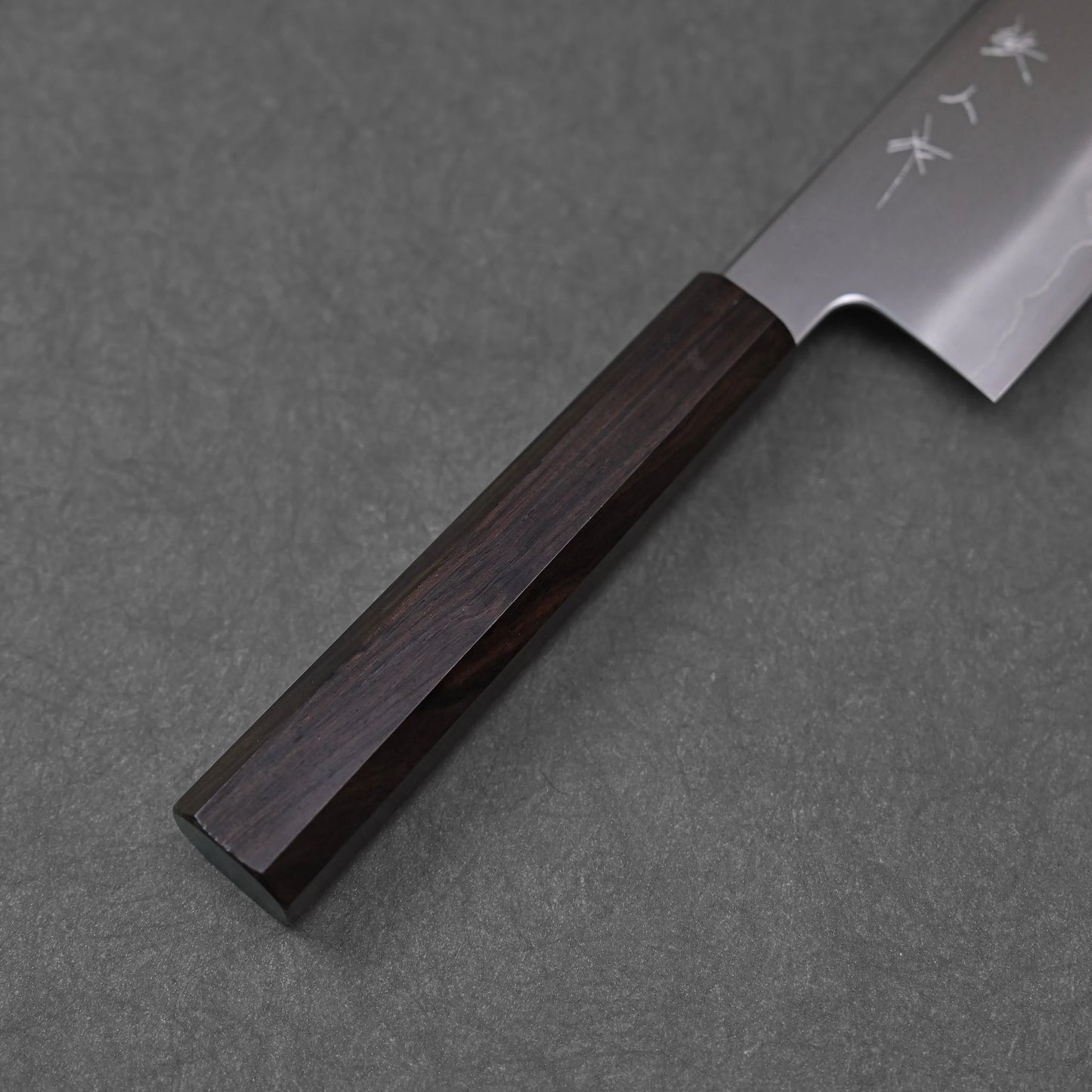 Close-up of a nakiri knife’s octagonal mono ebony handle; photographed to highlight the wood grain, dark tone, and craftsmanship.