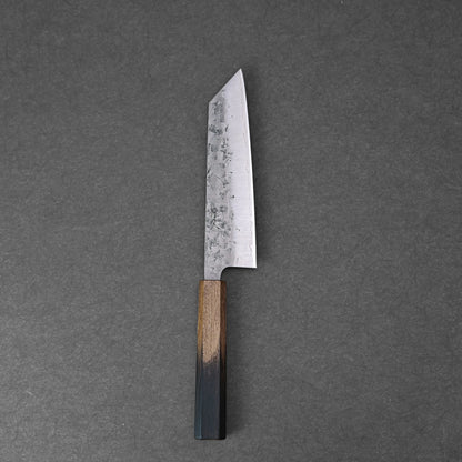 The Tsunehisa nashiji SLD bunka 170mm, featuring a straight-edged hammered SLD steel blade and a wooden handle, rests on a dark grey textured surface.