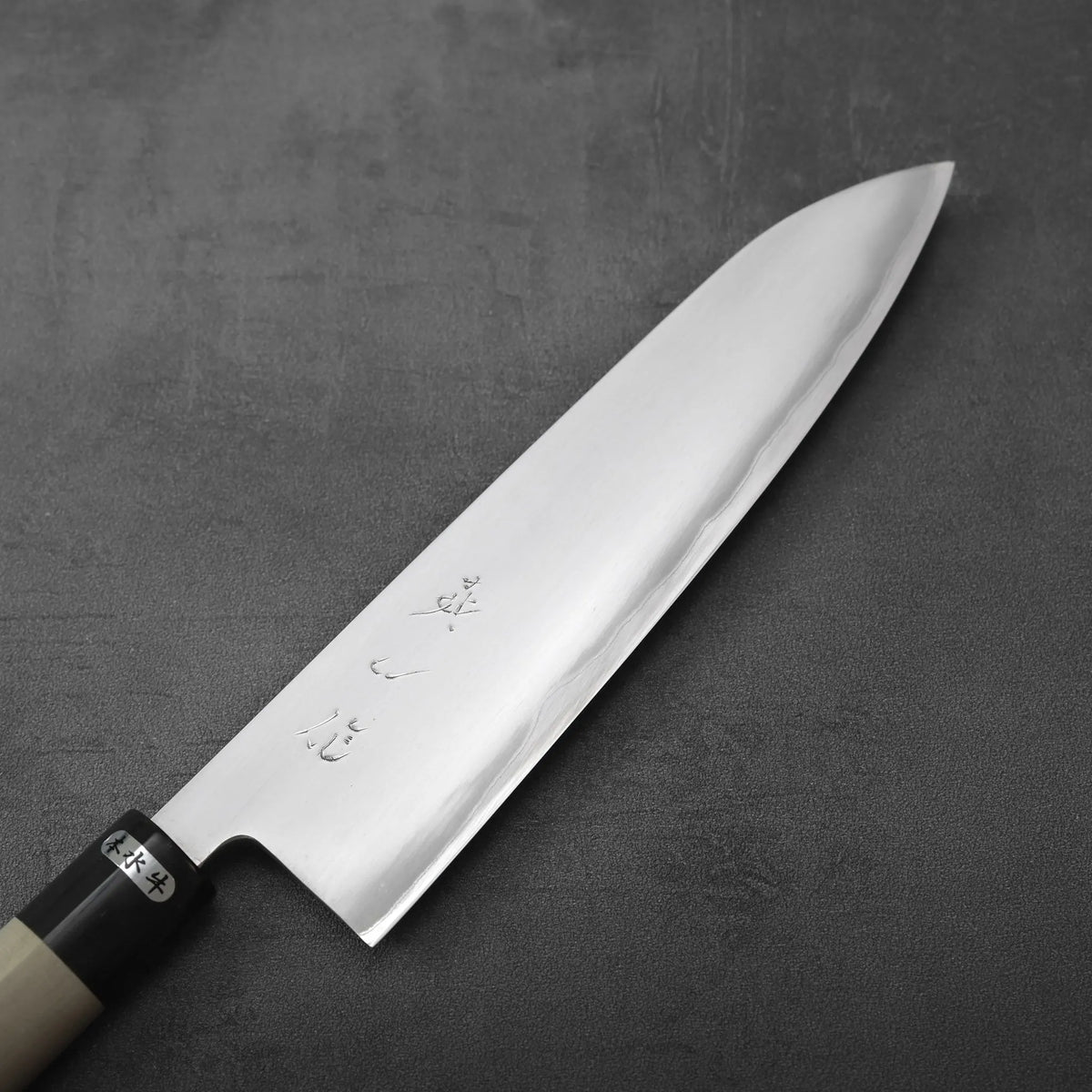Gyuto with a double-beveled blade, engraved Japanese characters, and a two-tone handle.
