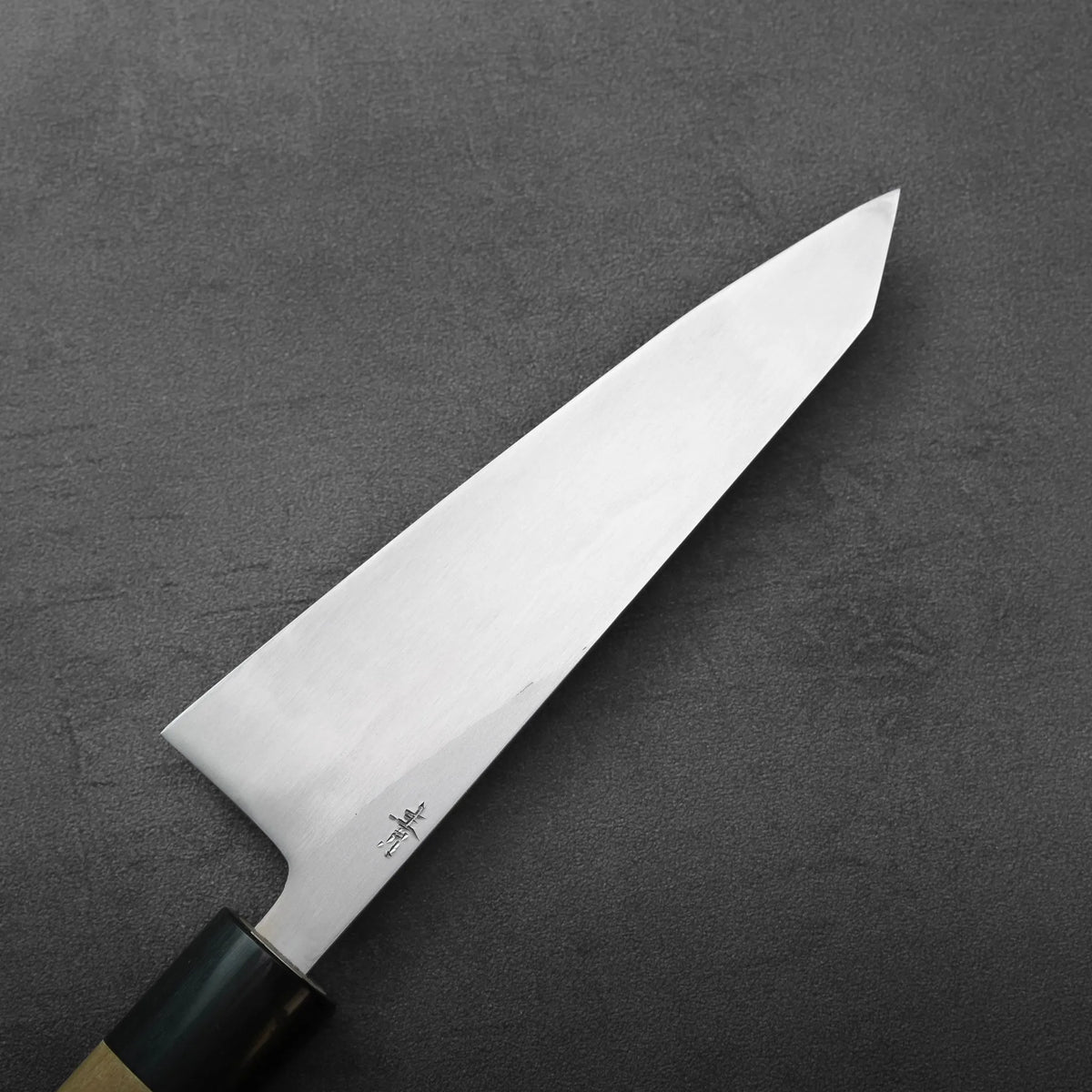 Honesuki 150mm knife with a pointed blade and a partial view of a dark handle.