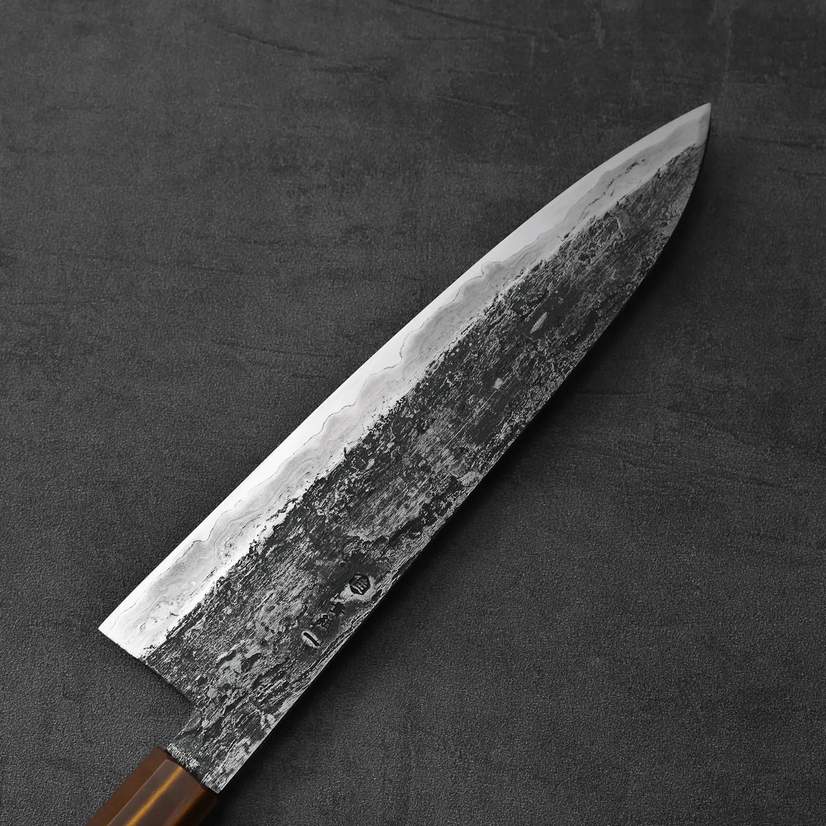 Close-up of a gyuto with a textured blade and wooden handle, extra tall at 58mm.