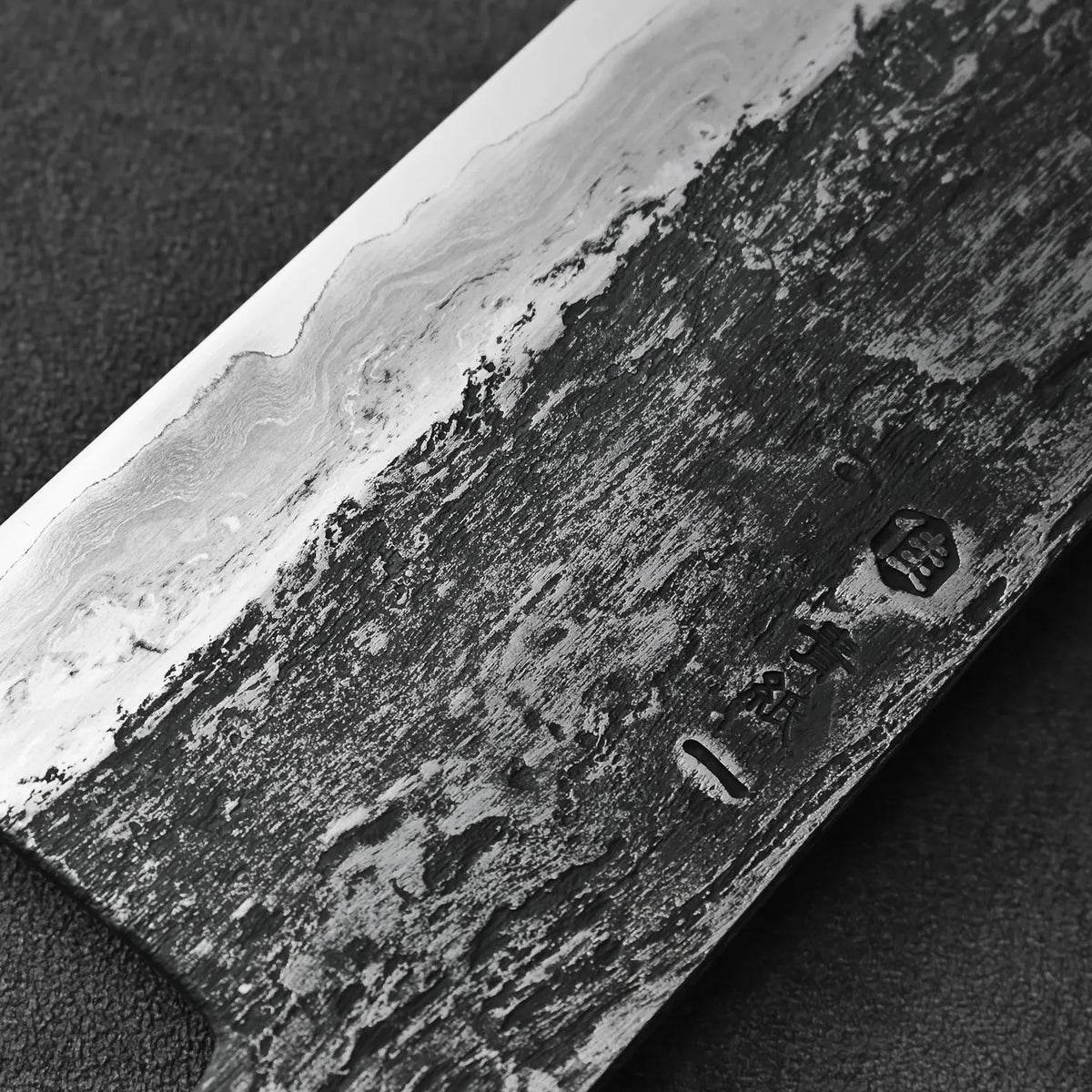 Close-up of a gyuto featuring an extra tall 58mm blade and wavy Damascus patterns.