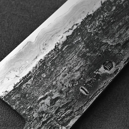 Close-up of a gyuto featuring an extra tall 58mm blade and wavy Damascus patterns.