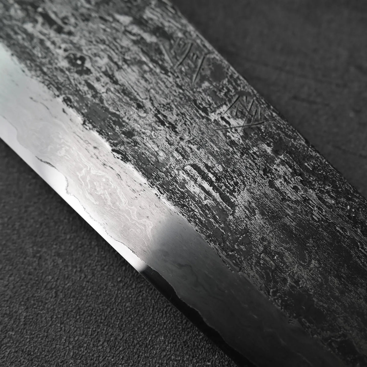 Gyuto blade shown in close-up, featuring extra tall aogami#1 steel with wrought iron cladding.