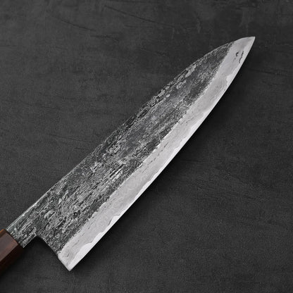 Gyuto with a textured blade and wrought iron cladding, shown in close-up highlighting its extra tall profile.