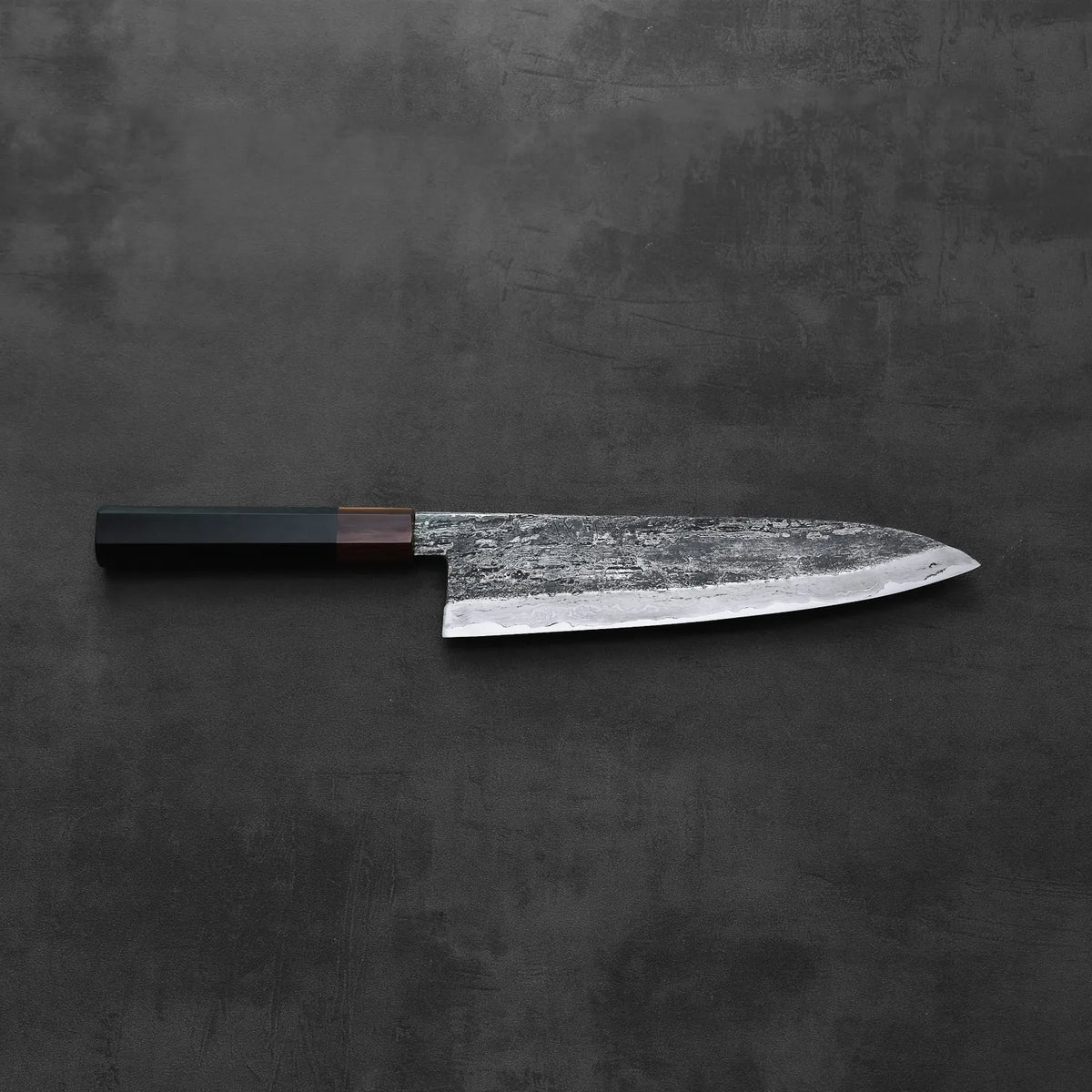 A gyuto with a dark handle is displayed, showing its extra tall blade and refined proportions.