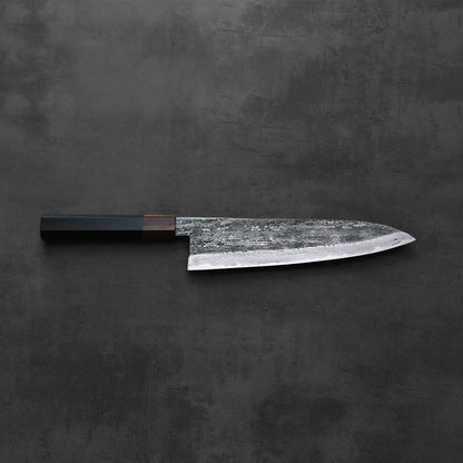 A gyuto with a dark handle is displayed, showing its extra tall blade and refined proportions.