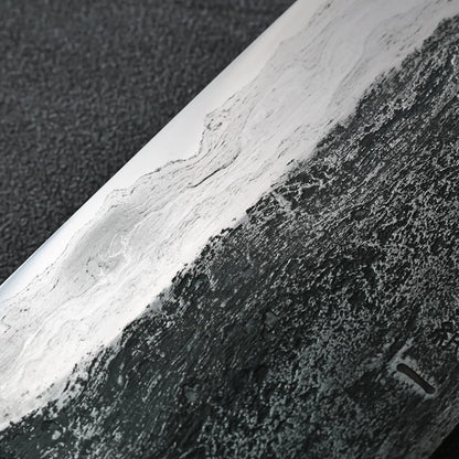 Gyuto with a wavy blade, illuminated so it gleams and stands out distinctly.
