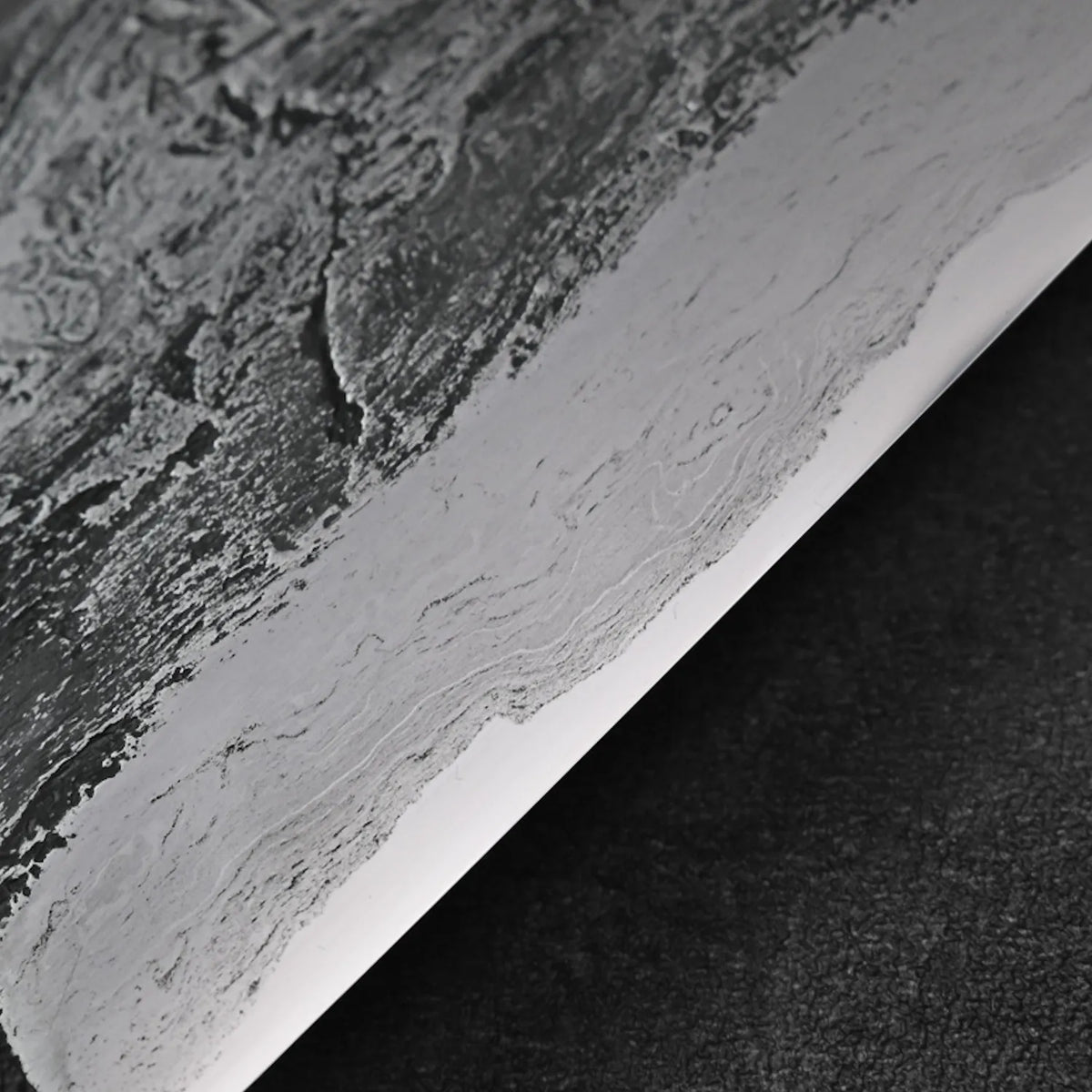 Close-up of gyuto with textured, layered iron cladding and visible detail on the blade’s finish.