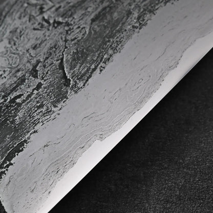 Close-up of gyuto with textured, layered iron cladding and visible detail on the blade’s finish.