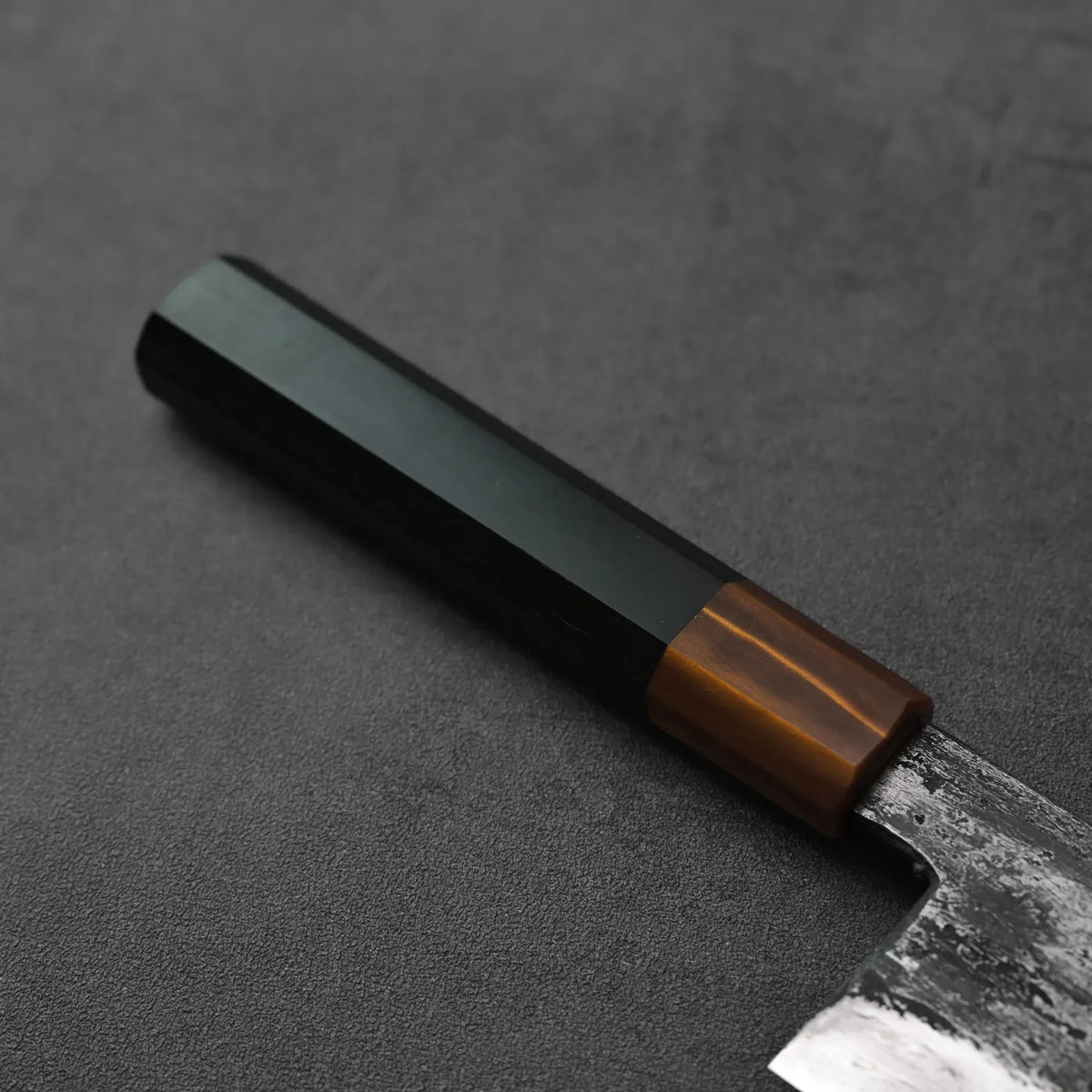 Gyuto with a dark hex handle, shown in close-up to display its tall 240x55mm blade.