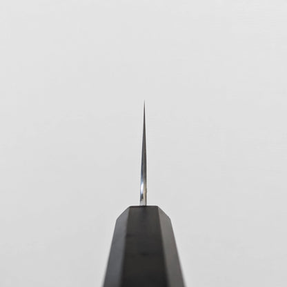 Japanese knife featuring a visible choil shot with a polished finish and damascus steel wave patterns extending into the choil area; photographed to highlight the edge transition and blade precision near the handle.