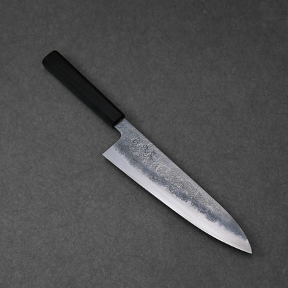 Japanese chef’s knife featuring damascus steel wave patterns and vertically engraved kanji characters near the handle; photographed at a standard angle to highlight the full blade and engraving placement.
