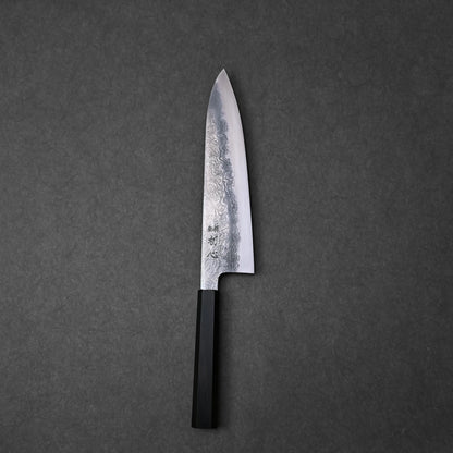Japanese chef’s knife with damascus steel blade showcasing layered wave patterns and vertically engraved kanji near the handle; paired with a black octagonal handle and photographed flat against a dark textured surface to highlight craftsmanship and design detail.