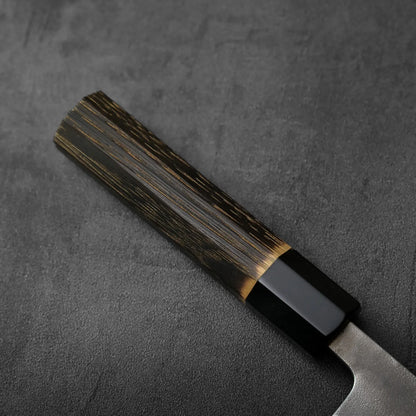 Close-up of a gyuto handle with black bolster, showing detail and grain along the length of the handle.