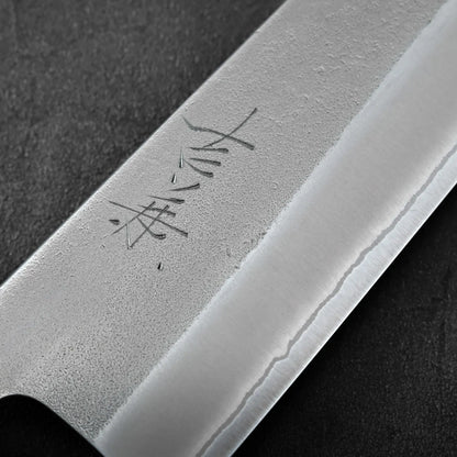 Close-up of a blade featuring kanji and nashiji finish, highlighting the distinct shape of a gyuto.