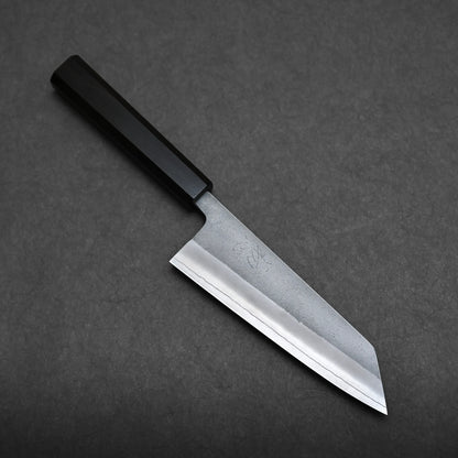 A bunka knife with a rectangular, black handle and a wide, angular blade is placed on a dark grey surface. This compact all-purpose Japanese knife is perfect for precision tasks in the kitchen.