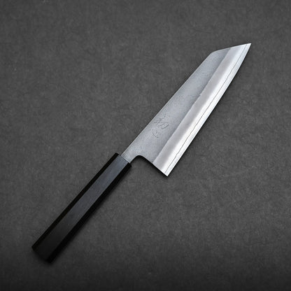 A Hatsukokoro x Yoshikane nashiji SKD bunka 165mm with a straight-edged blade and a dark octagonal handle is placed on a dark textured surface.