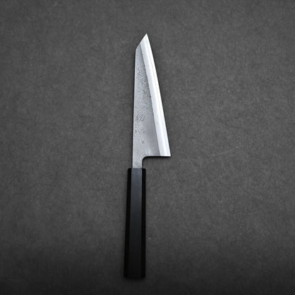A Japanese-style honesuki knife with a straight-edged blade and a black handle is placed on a dark gray textured surface.