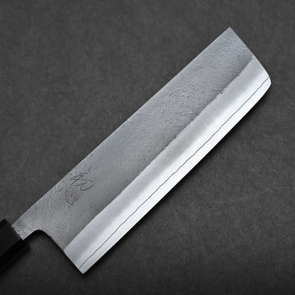 A close-up of a Japanese-style kitchen knife with a rectangular blade, featuring a textured upper half and polished cutting edge, placed on a dark gray surface.