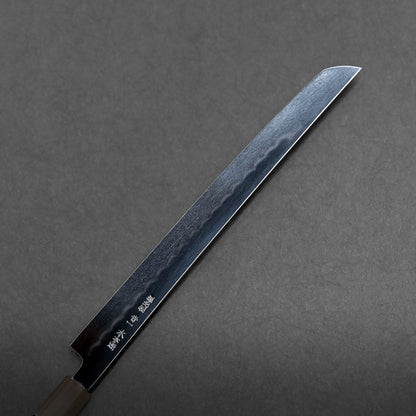 A mizuhonyaki aogami#1 sakimaru Japanese knife with a straight-edged, single bevel blade and engraved characters near the handle, displayed diagonally on a dark gray background.