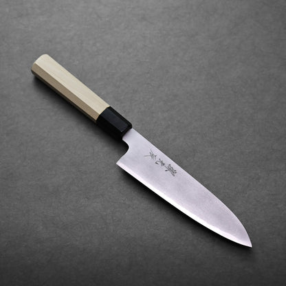 A Japanese-style gyuto knife with a light wooden handle and a sharp, pointed stainless steel blade featuring engraved kanji characters, placed on a dark gray surface.