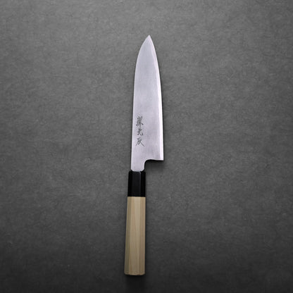 A Japanese gyuto knife with a light wooden handle and a sharp, pointed stainless steel blade featuring engraved Japanese characters, displayed on a dark gray textured surface.