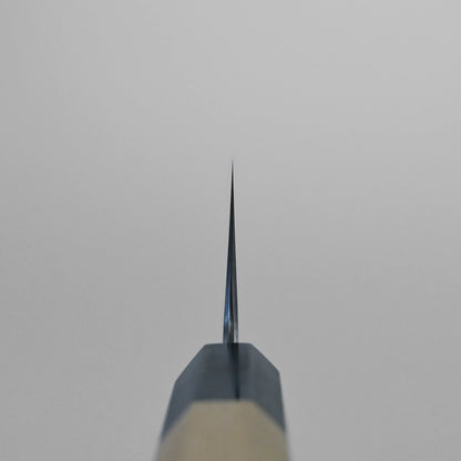 Choil shot of the gyuto knife, shot from the handle end with the blade pointing upwards against a plain light gray background.