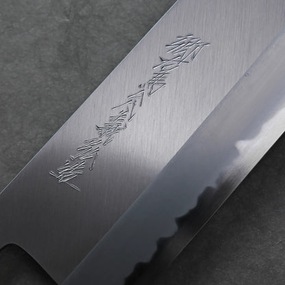 Close-up of a Tanaka 210mm nakiri blade with kanji characters engraved on the polished metal, displayed against a dark background.