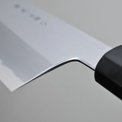 Close-up of choil finish of a Tanaka AS gyuto, set against a plain gray background.