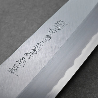 Close-up of a Tanaka AS gyuto blade with engraved kanji characters and a visible wavy temper line, set against a dark background.