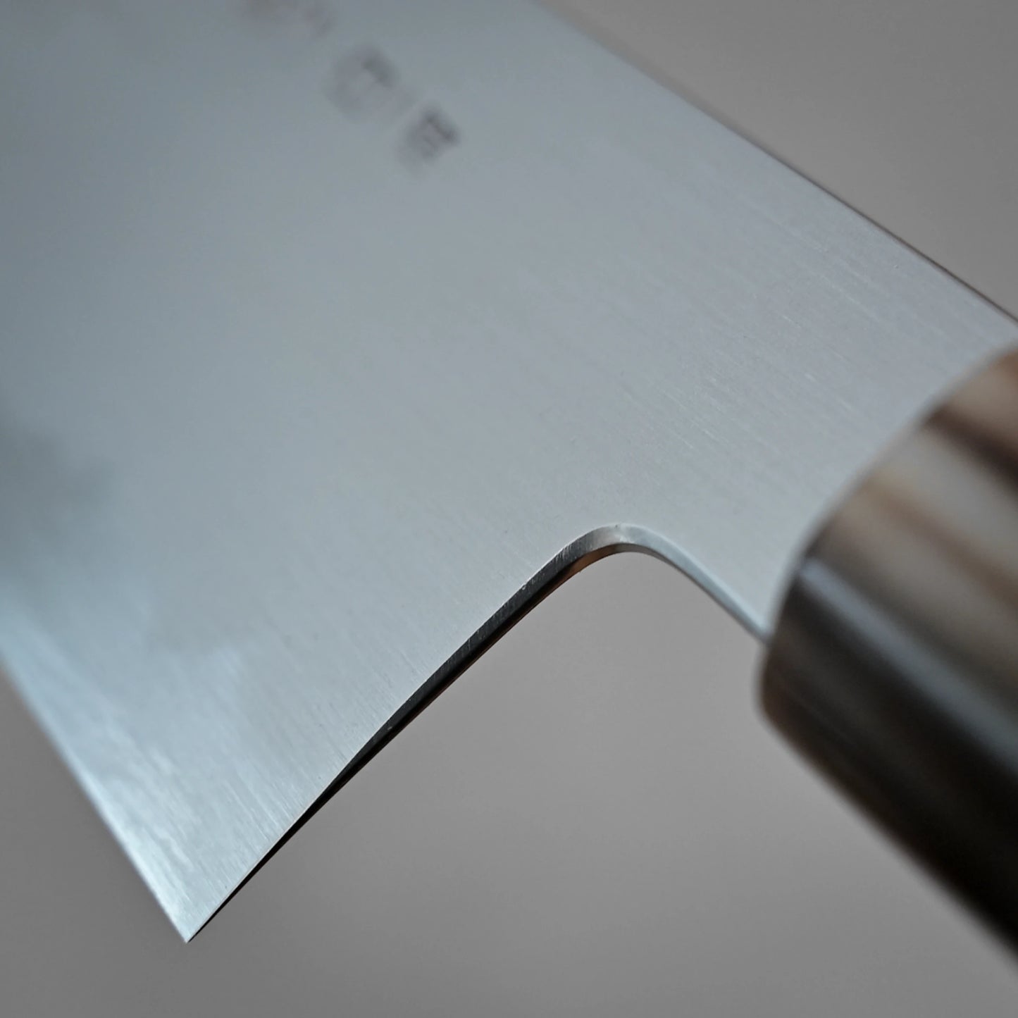 Close-up of the blade and handle of the Yoshikazu Tanaka shirogami#1 kiritsuke gyuto 225mm, a stainless steel kitchen knife by Yoshikazu Tanaka, crafted in Sakai, Japan, showing its smooth, reflective surface against a neutral background.