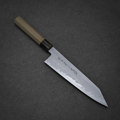The Yoshikazu Tanaka shirogami#1 kiritsuke gyuto 225mm is a Japanese-style kitchen knife with a wooden handle and pointed steel blade engraved with Japanese characters, crafted by Yoshikazu Tanaka and shown on a dark textured surface.
