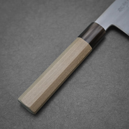 Close-up of the handle and blade of a Yoshikazu Tanaka shirogami#1 kiritsuke gyuto 225mm kitchen knife. The light wood handle has a dark section near the blade, crafted in Sakai, Japan, shown against a plain gray background.