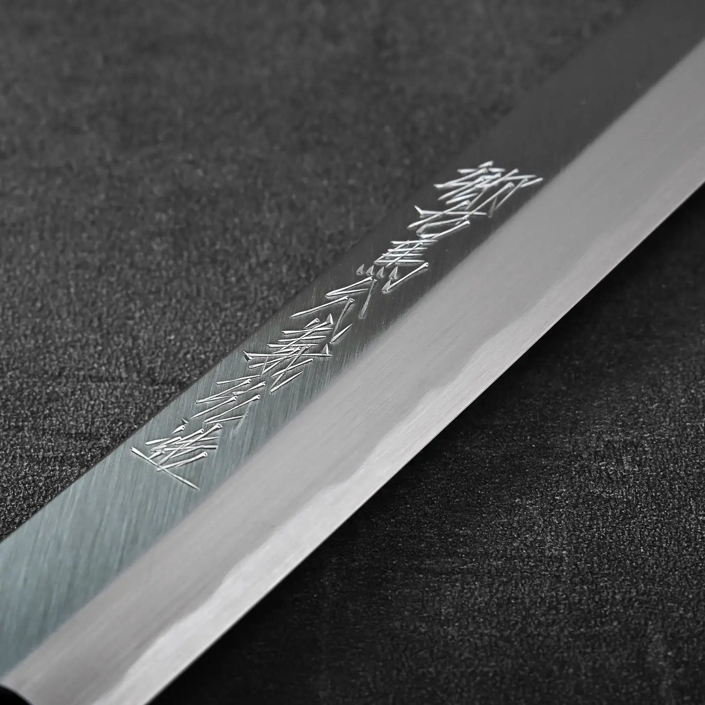 Close-up of a sakimaru sujihiki blade featuring kanji, highlighting the distinct curvature and edge profile.