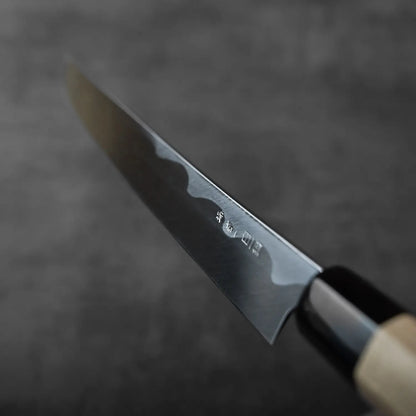 Close-up of a sakimaru sujihiki with wooden handle, engraved blade, and saya shown alongside the knife.