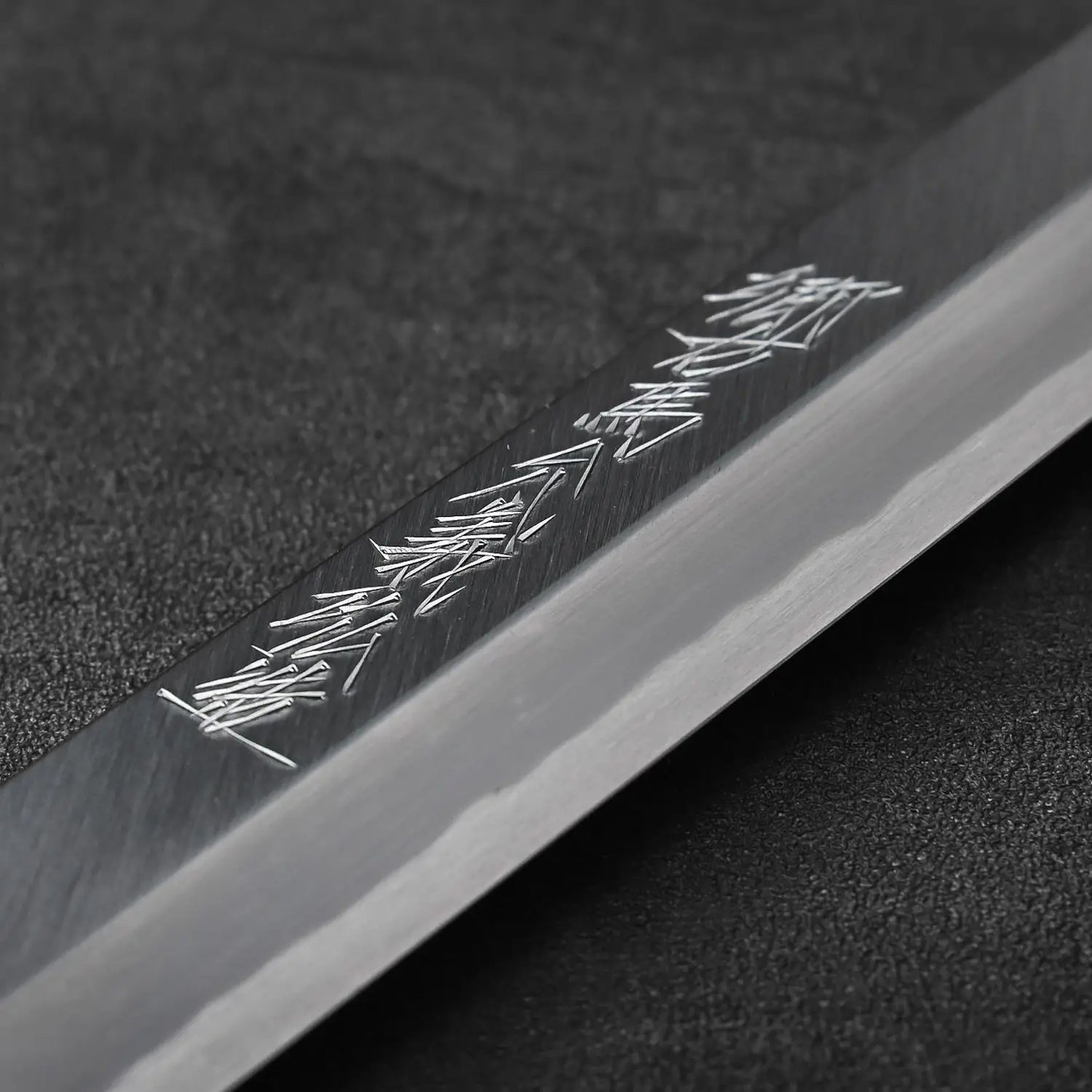 Close-up of a sakimaru sujihiki blade, 300mm long, featuring Japanese characters on its surface.