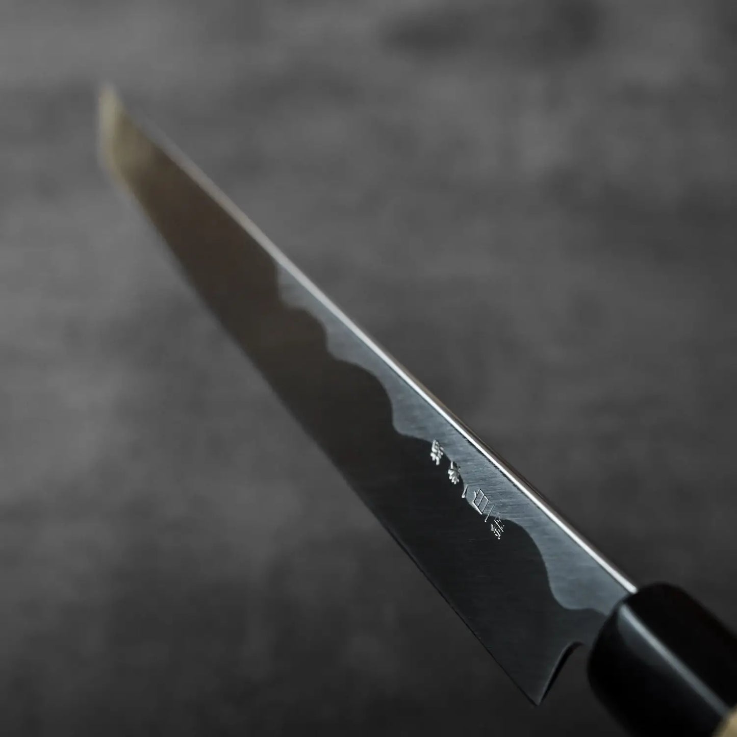 Close-up of sakimaru sujihiki with saya, showing distinctive blade engravings and detailed metalwork.