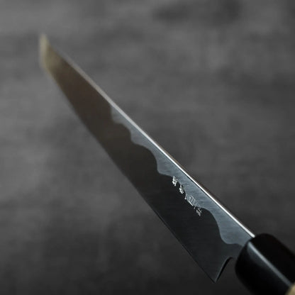 Close-up of sakimaru sujihiki with saya, showing distinctive blade engravings and detailed metalwork.