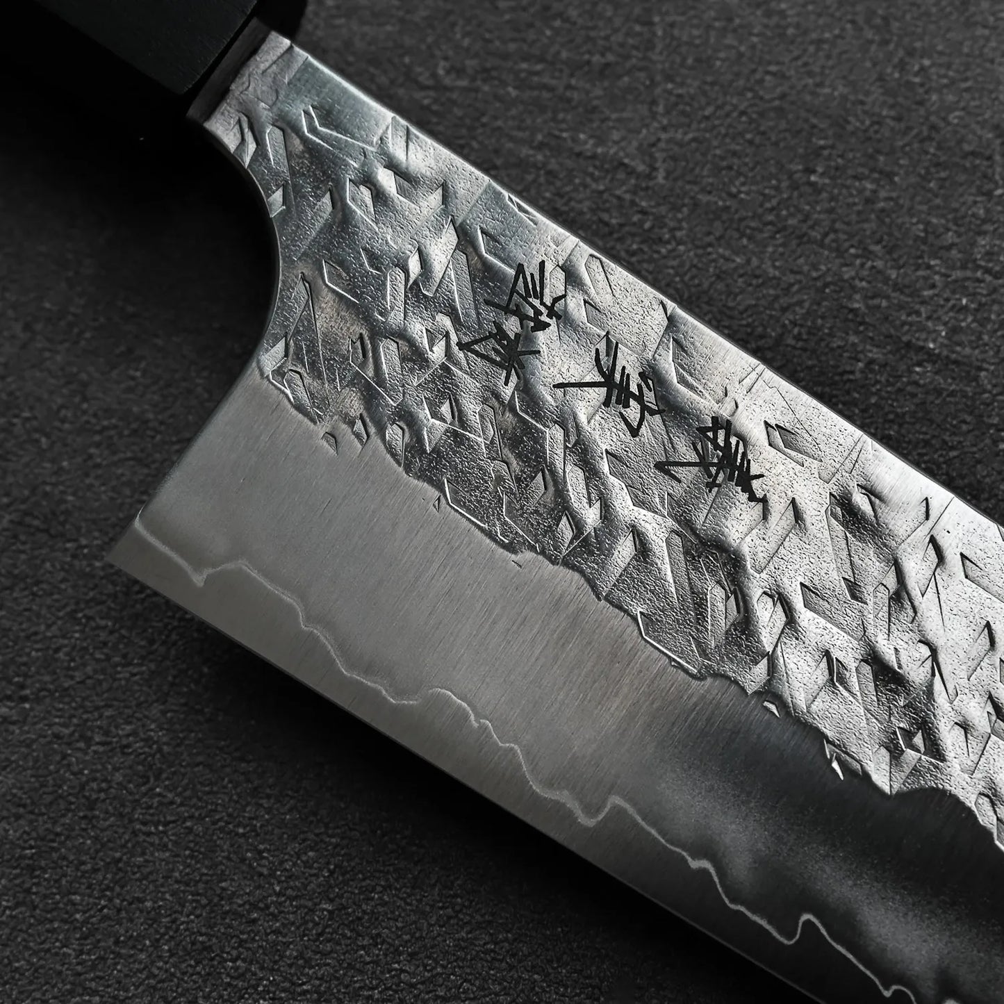 Gyuto with a textured blade and engraved kanji, shown in close-up to highlight its detailed finish.