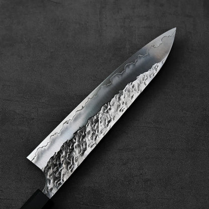 Close-up of gyuto blade with textured finish, showcasing detailed metal patterns and craftsmanship.